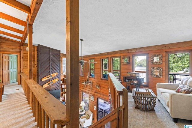 carpeted living room with wood walls, vaulted ceiling, and a textured ceiling