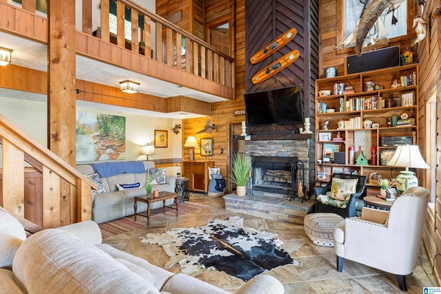 tiled living room featuring a fireplace, wood walls, and a high ceiling