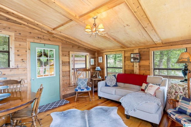 living room with lofted ceiling with beams, a chandelier, light hardwood / wood-style floors, and a healthy amount of sunlight