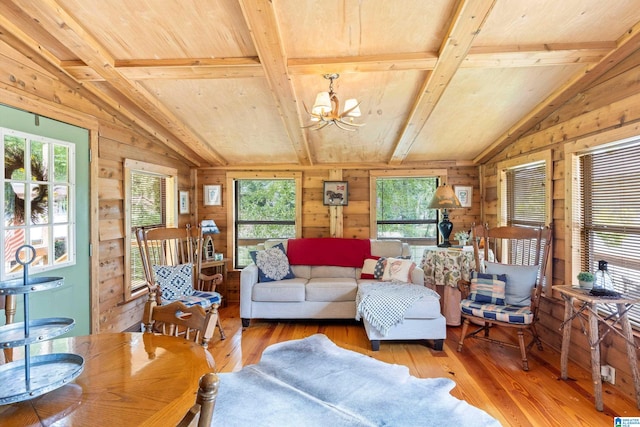 living room with a wealth of natural light, wooden walls, vaulted ceiling with beams, and hardwood / wood-style flooring