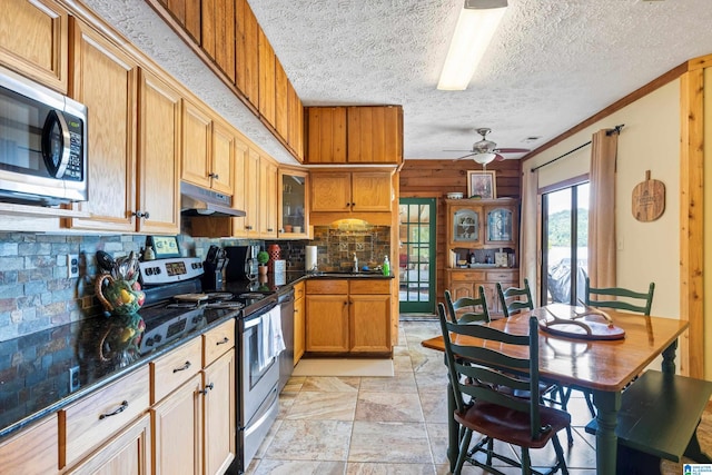 kitchen with appliances with stainless steel finishes, decorative backsplash, a textured ceiling, light tile patterned floors, and ceiling fan