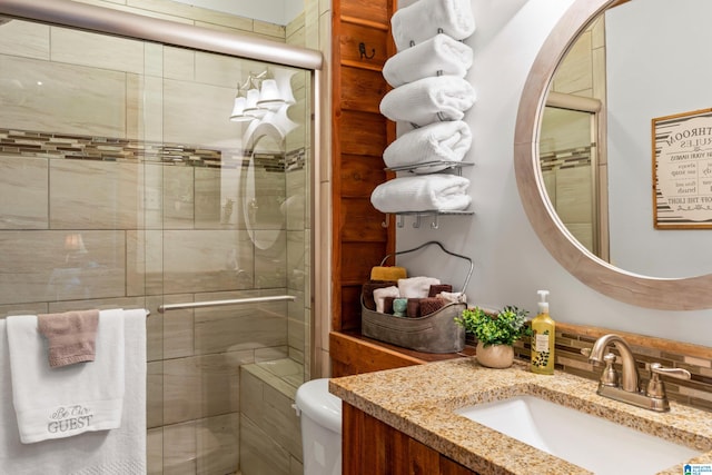 bathroom with toilet, a shower with door, and vanity