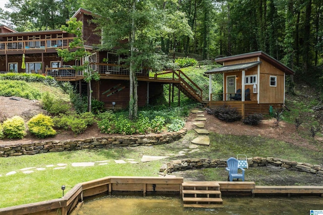 back of property featuring an outbuilding and a deck with water view