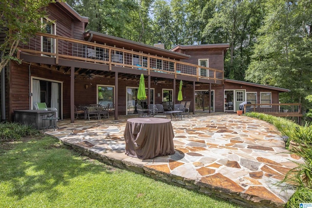 back of property featuring a deck, a patio, and a lawn