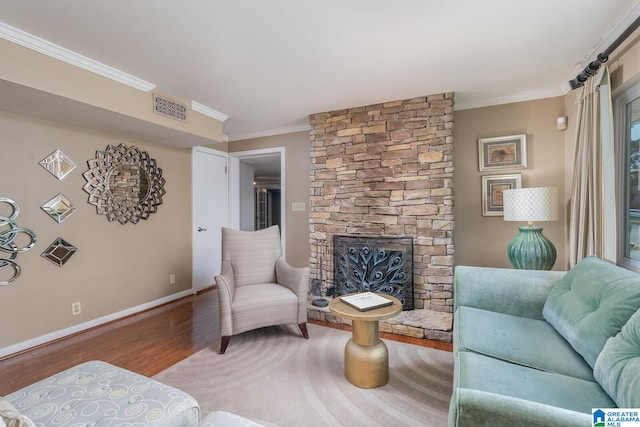 living room with ornamental molding, wood-type flooring, and a stone fireplace