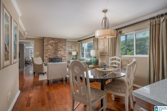 dining space with dark hardwood / wood-style floors, a fireplace, and ornamental molding