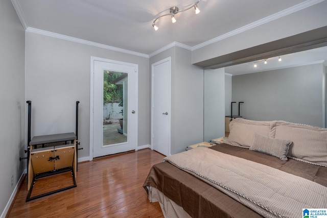 bedroom featuring hardwood / wood-style flooring, access to exterior, crown molding, and rail lighting