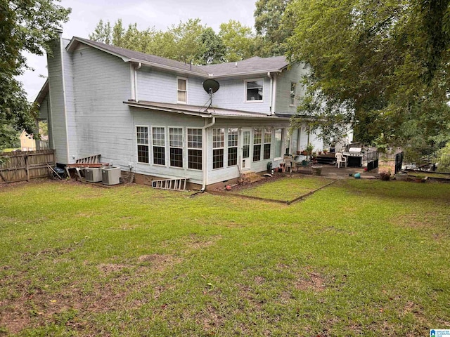 rear view of property featuring a patio, a sunroom, central AC, and a lawn