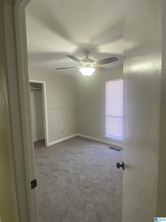 unfurnished bedroom with ceiling fan, carpet flooring, and a textured ceiling