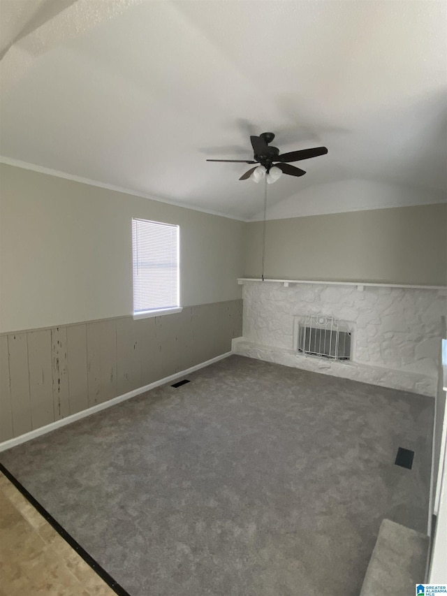 unfurnished living room featuring a stone fireplace, lofted ceiling, carpet flooring, ornamental molding, and ceiling fan