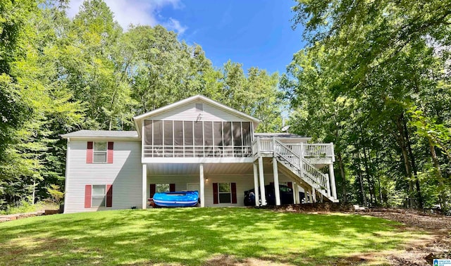 rear view of house with a wooden deck, a lawn, and a sunroom