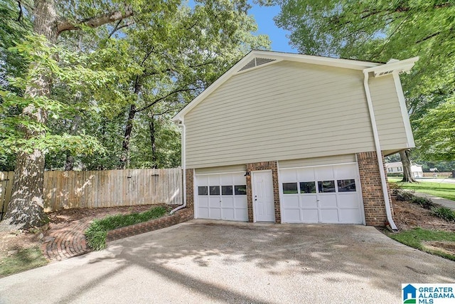 garage featuring concrete driveway and fence