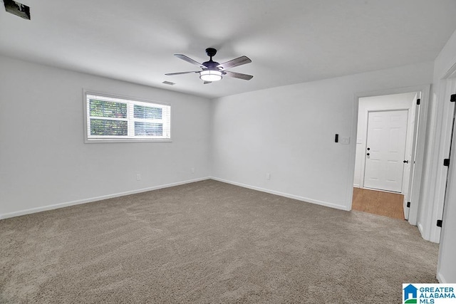 carpeted empty room featuring ceiling fan, visible vents, and baseboards