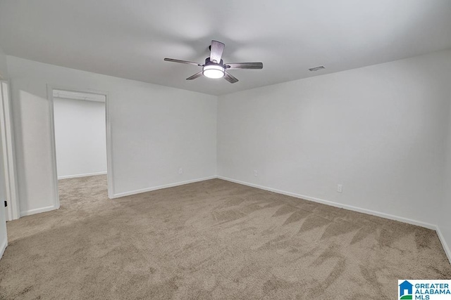 spare room with light carpet, ceiling fan, visible vents, and baseboards