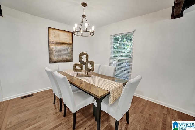 dining area with a notable chandelier, baseboards, visible vents, and wood finished floors