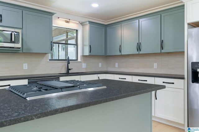 kitchen with backsplash, appliances with stainless steel finishes, and sink