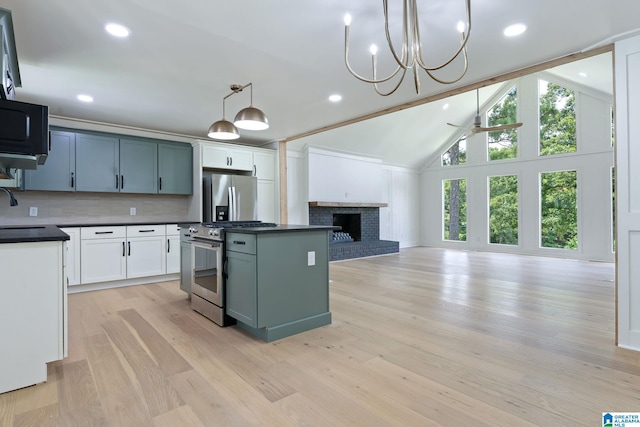 kitchen with decorative light fixtures, a fireplace, ceiling fan with notable chandelier, light hardwood / wood-style floors, and appliances with stainless steel finishes