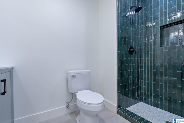 bathroom with vanity, tile patterned flooring, a tile shower, and toilet