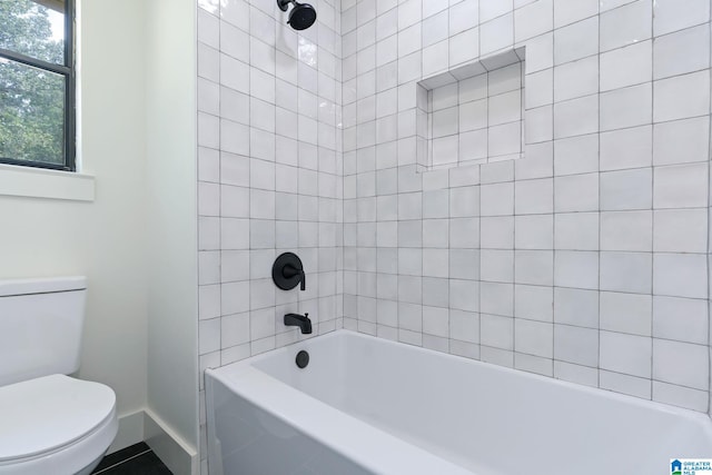 bathroom featuring tiled shower / bath combo and toilet