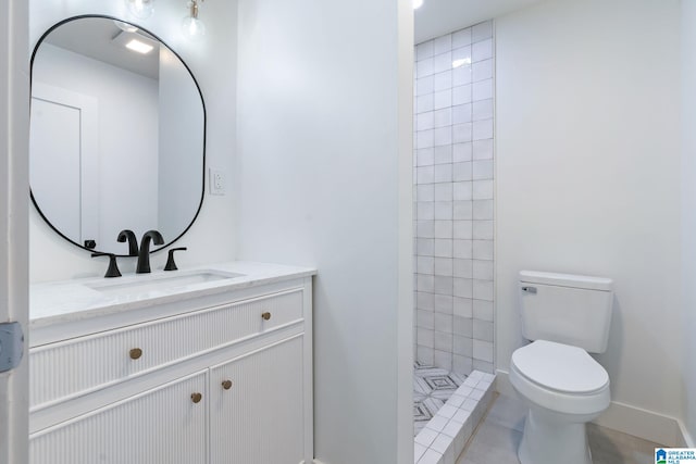 bathroom featuring tile patterned flooring, toilet, vanity, and a tile shower