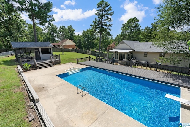 view of swimming pool featuring a patio, a deck, a lawn, and a diving board