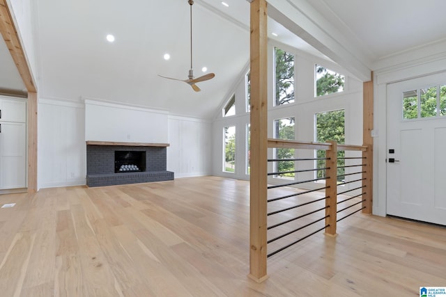 unfurnished living room with ceiling fan, a brick fireplace, light hardwood / wood-style floors, and high vaulted ceiling