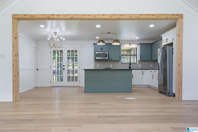 kitchen featuring appliances with stainless steel finishes, pendant lighting, tasteful backsplash, and light hardwood / wood-style floors