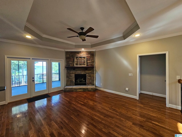 unfurnished living room with a raised ceiling, hardwood / wood-style floors, ceiling fan, and a stone fireplace