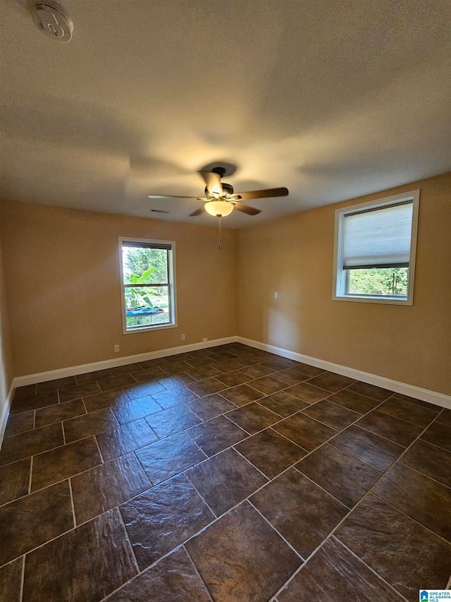 tiled empty room featuring plenty of natural light and ceiling fan