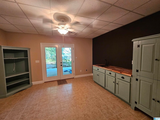 unfurnished living room with ceiling fan, light tile patterned floors, a drop ceiling, and sink