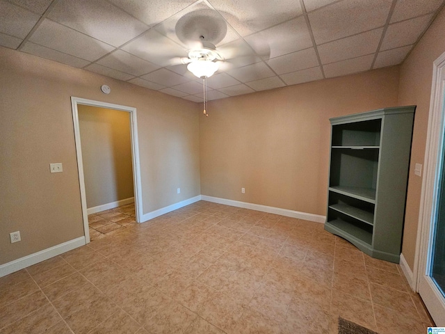 empty room with ceiling fan, a drop ceiling, and tile patterned flooring