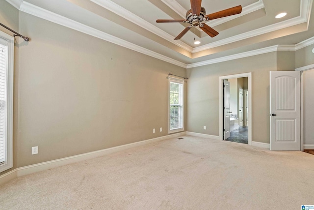 unfurnished bedroom featuring ornamental molding, light carpet, a tray ceiling, and ceiling fan