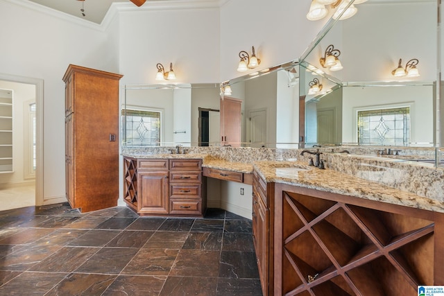 bathroom with crown molding, a towering ceiling, a wealth of natural light, and vanity