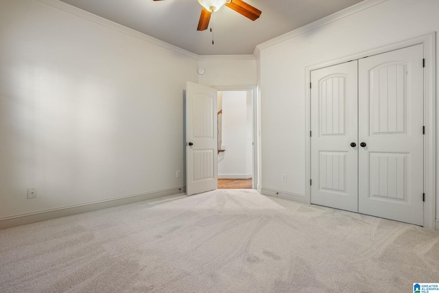 unfurnished bedroom with light carpet, crown molding, a closet, and ceiling fan