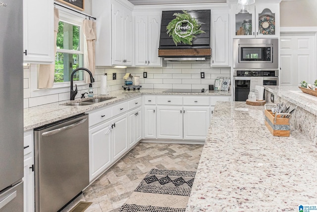 kitchen featuring appliances with stainless steel finishes, white cabinets, a sink, and glass insert cabinets