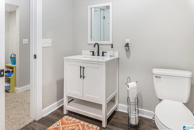 bathroom with toilet, baseboards, wood finished floors, and vanity