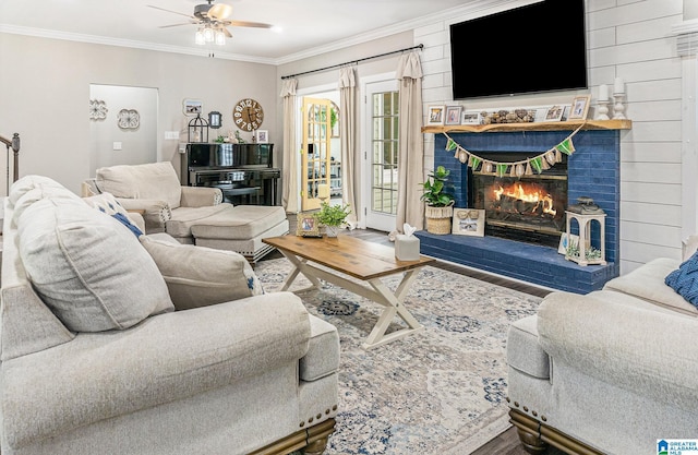 living room featuring a fireplace, wood finished floors, a ceiling fan, and crown molding