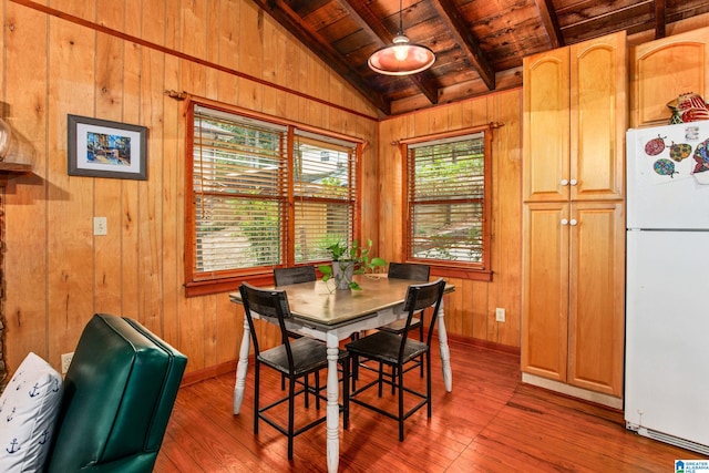 dining area featuring wooden walls, baseboards, lofted ceiling with beams, wood ceiling, and hardwood / wood-style floors