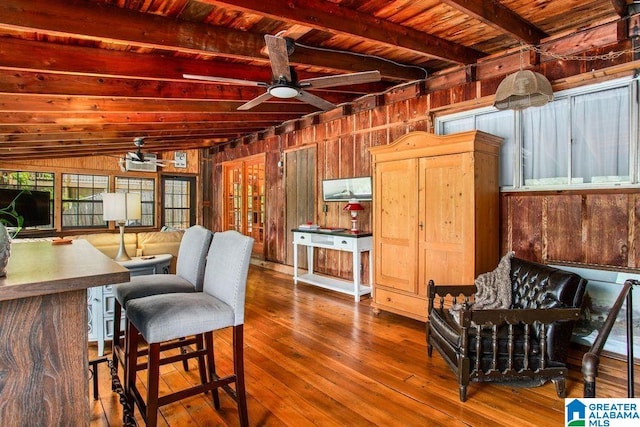 kitchen with wood ceiling, ceiling fan, wooden walls, beamed ceiling, and hardwood / wood-style flooring