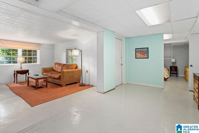 living area featuring concrete floors and a drop ceiling