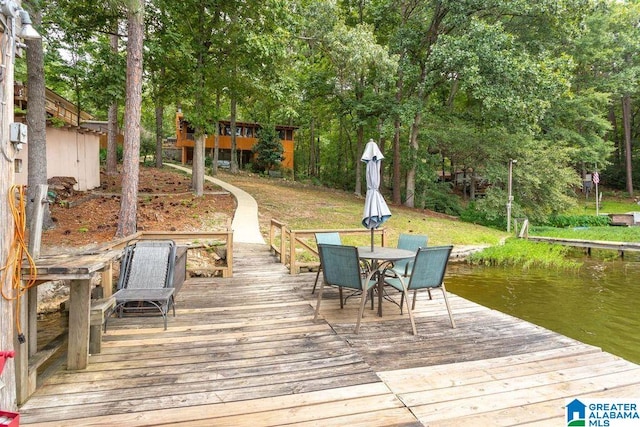 dock area featuring outdoor dining space, a water view, and a lawn