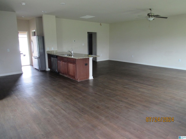 kitchen featuring dark wood-type flooring, a ceiling fan, a sink, open floor plan, and appliances with stainless steel finishes