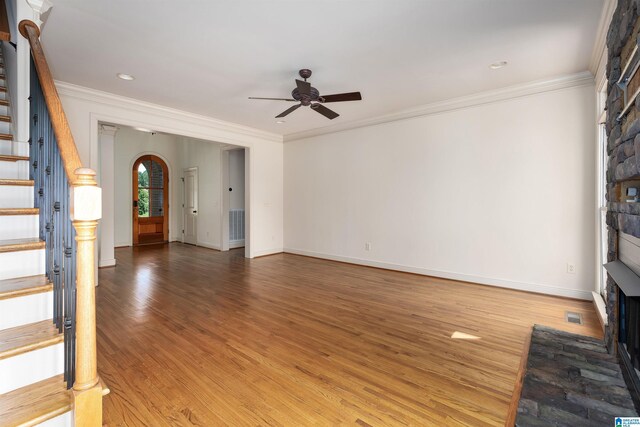 unfurnished living room featuring a fireplace, ceiling fan, light wood-type flooring, and crown molding