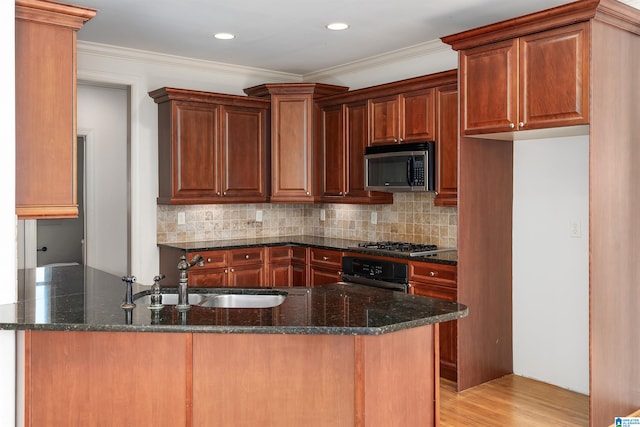 kitchen featuring dark stone counters, light hardwood / wood-style flooring, appliances with stainless steel finishes, and kitchen peninsula