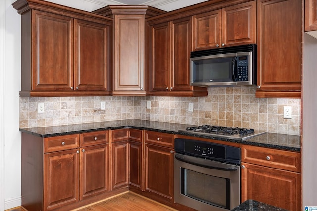 kitchen featuring light hardwood / wood-style floors, dark stone counters, decorative backsplash, and stainless steel appliances