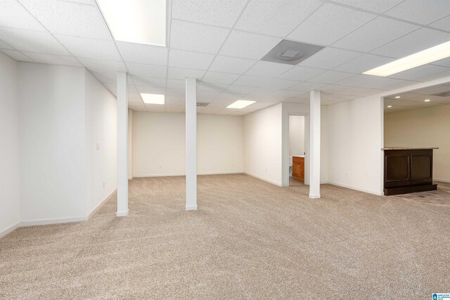 basement featuring light colored carpet and a paneled ceiling