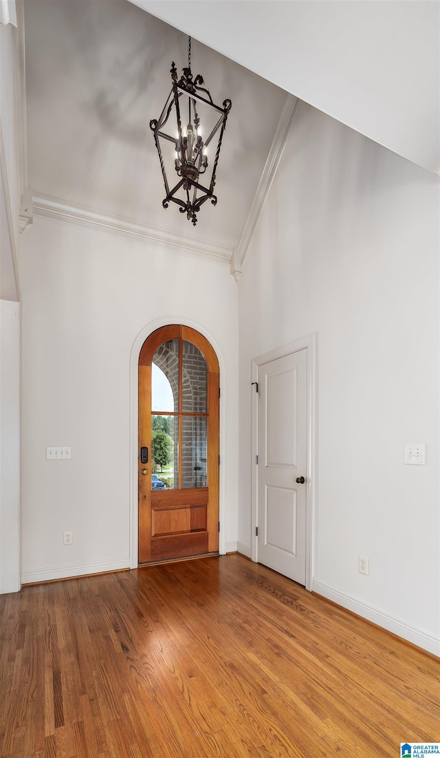 entrance foyer featuring a notable chandelier, crown molding, and hardwood / wood-style floors