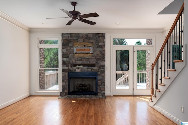 unfurnished living room with crown molding, a stone fireplace, hardwood / wood-style floors, and ceiling fan