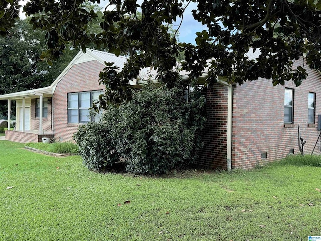 view of side of home with brick siding, crawl space, an attached garage, and a lawn