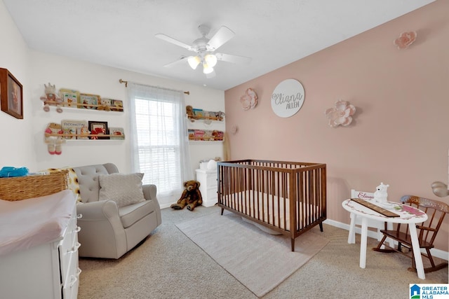 carpeted bedroom featuring a nursery area and ceiling fan